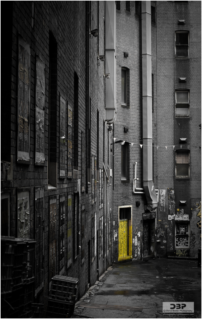 A yellow door at the end of a service alleyway in Melbourne